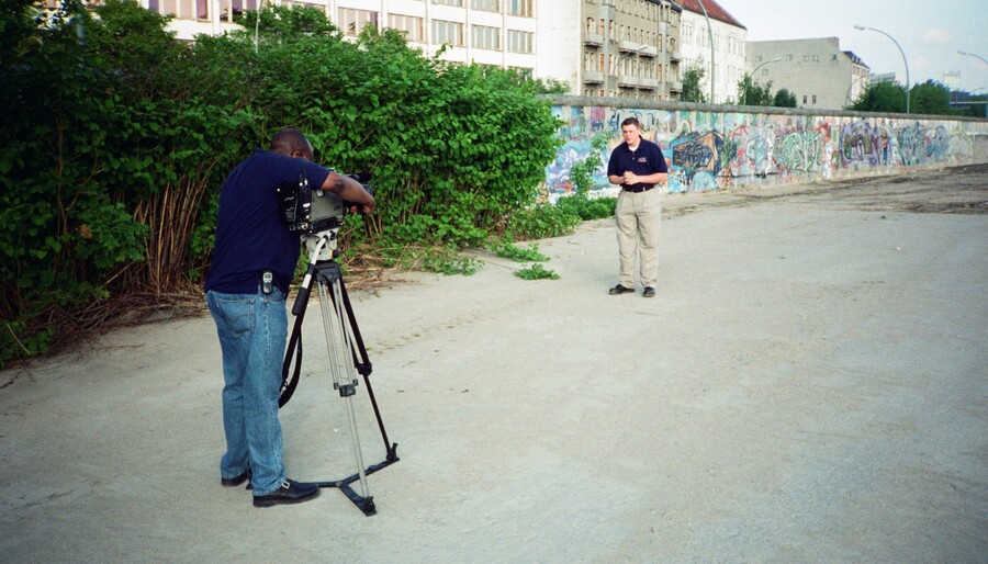 A cameraman filming Kane Farabaugh at the Berlin Wall